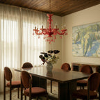 Clérachic crystal chandelier glows warm red-toned above a wood-panelled dining room with sheer linen curtains.