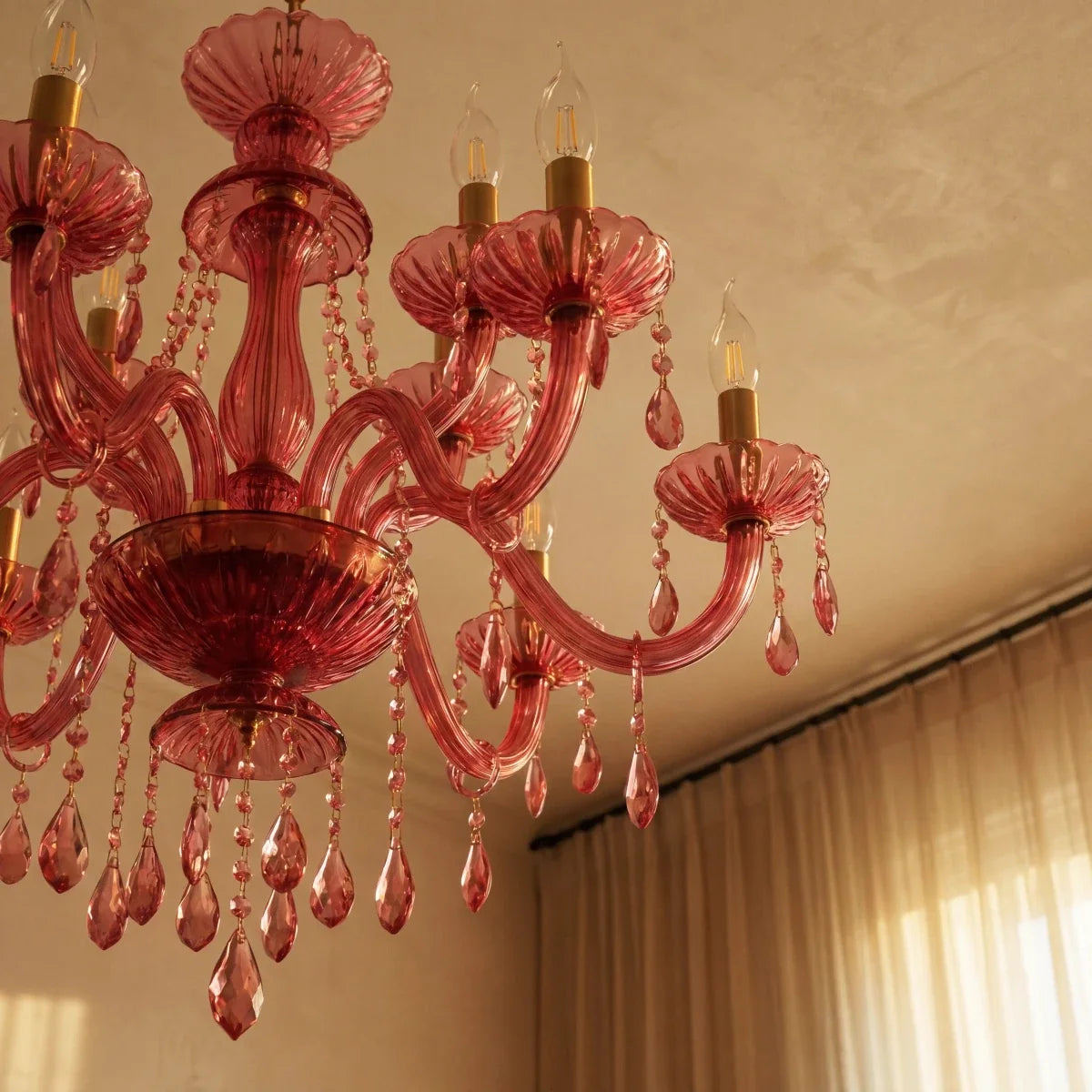 Clérachic pink crystal chandelier detail: brass candle sleeves, glass arms and crystal drops in soft daylight.