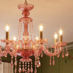 Clérachic pink crystal chandelier detail: six brass candle arms and cascading crystal drops in warm light.