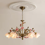 Clérachic chandelier hung from a white fluted ceiling rose, its frosted glass roses lit warmly above pink ceramic flowers and leaves.