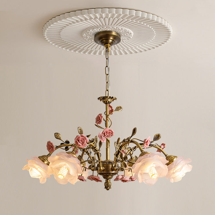 Clérachic chandelier hung from a white fluted ceiling rose, its frosted glass roses lit warmly above pink ceramic flowers and leaves.