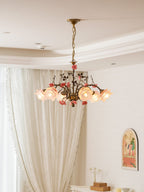 Clérachic chandelier lit in a cream room with lace-edged curtains, a small console with a candle holder and an arched picture.