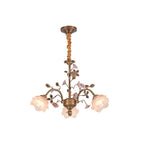 Clérachic chandelier with a fabric-wrapped chain on a white backdrop, ceramic roses in soft pink and frosted glass rose shades lit.