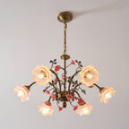 Clérachic chandelier with pink glass roses lit on a pale backdrop, seen from slightly below, with gold arms and pink ceramic roses.