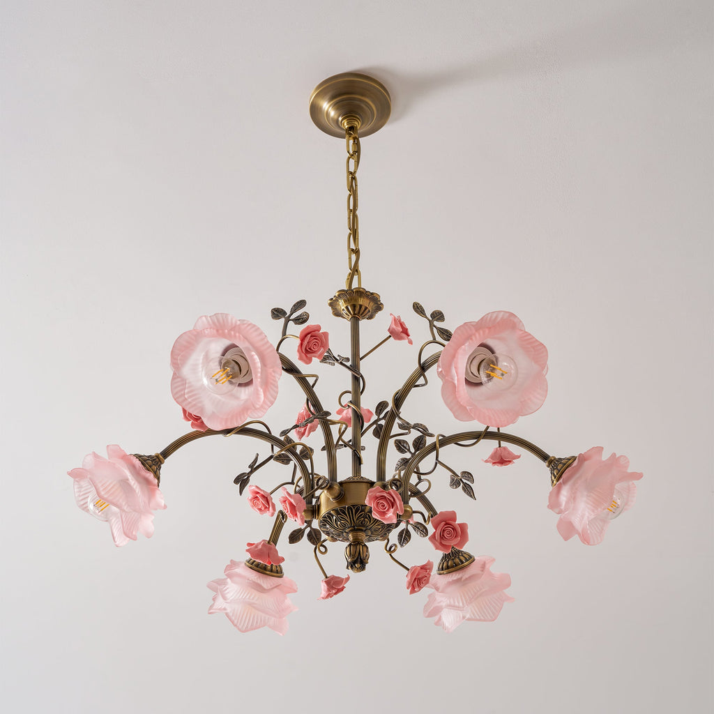 Clérachic rose chandelier on a pale backdrop, with pink glass shades and gold arms, with its glass roses tilted upward.