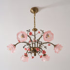 Clérachic rose chandelier on a pale backdrop, with pink glass shades and gold arms, with its glass roses tilted upward.
