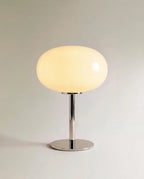 Clérachic opal glass table lamp with a glowing white globe shade on a slender chrome pedestal base.