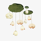 Clérachic pendant chandelier of pink and white bud-shaped shades hanging on thin cords from green lily-pad canopies, on a plain white backdrop.