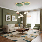 Bud-shaped pendants from Clérachic hang from green lily-pad canopies in a sage-green living room with a cream sofa and olive armchairs.