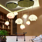Pink-edged and white water-lily shades from Clérachic hang at different heights beneath lily-pad canopies, over a desk in a study with a bookcase.