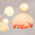 Close view of a large pink-edged water-lily shade from this Clérachic chandelier, glowing warm with smaller white buds hanging around it.