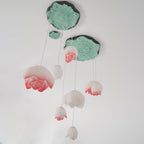 Unlit and seen from below, the Clérachic water-lily pendants show white and pink-tipped petals under green lily-pad canopies with a faint halo.