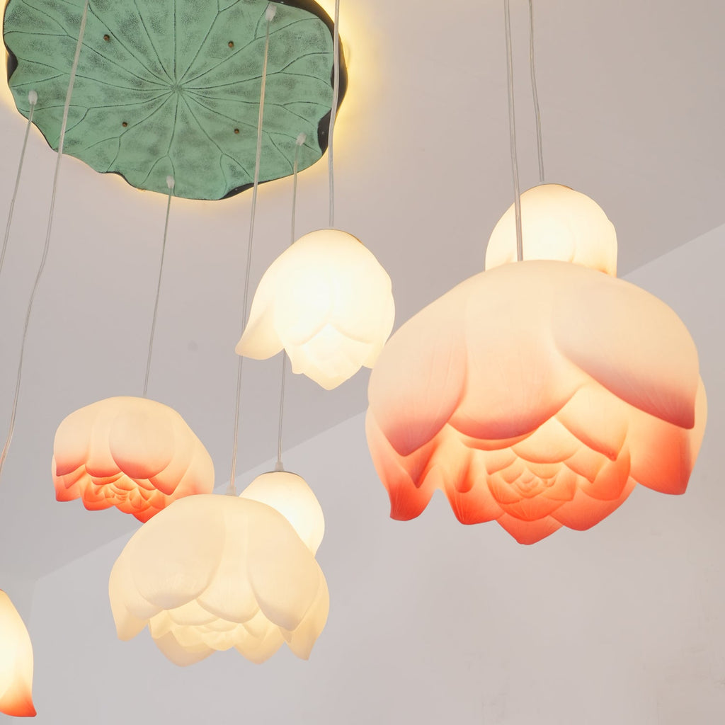 Close view of pink-tipped water-lily shades from this Clérachic chandelier, with layered ribbed petals glowing warm below a green lily-pad canopy.