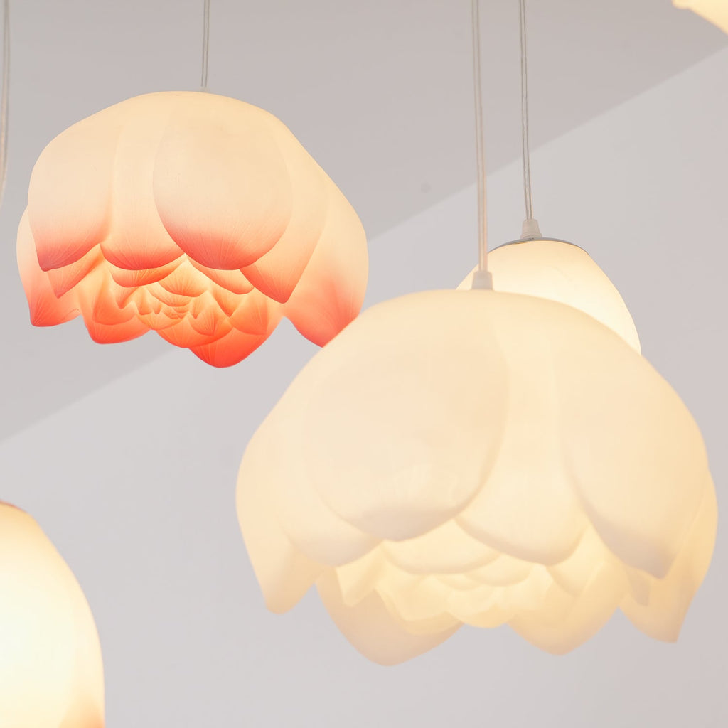 Close view of two water-lily shades from this Clérachic chandelier, one glowing cream and one tipped with coral, showing their layered petals.