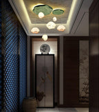 Along a dark hallway with a blue lattice screen, a Clérachic water-lily pendant cluster glows beneath a recessed ceiling with a warm cove light.