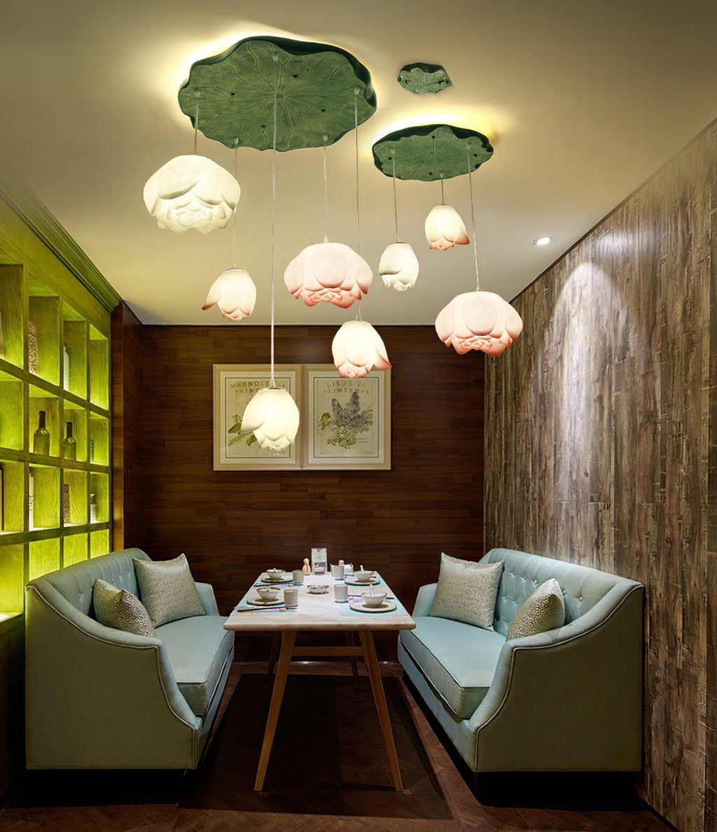 A Clérachic water-lily pendant cluster hangs in a private dining booth with teal banquettes, a small table and warm green-yellow cove lighting.