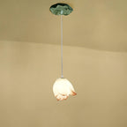A single Clérachic water-lily pendant with a closed white bud and a faint coral tip, hanging from a small green lily-pad canopy.