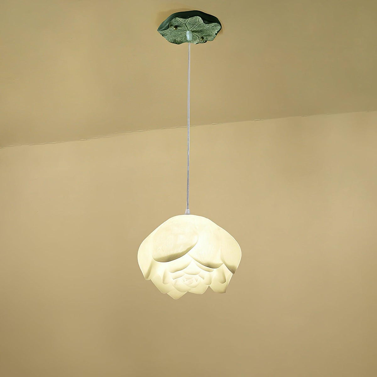 A single Clérachic water-lily pendant with a wider white bloom, hanging on a thin cord from a small green lily-pad canopy against a cream wall.