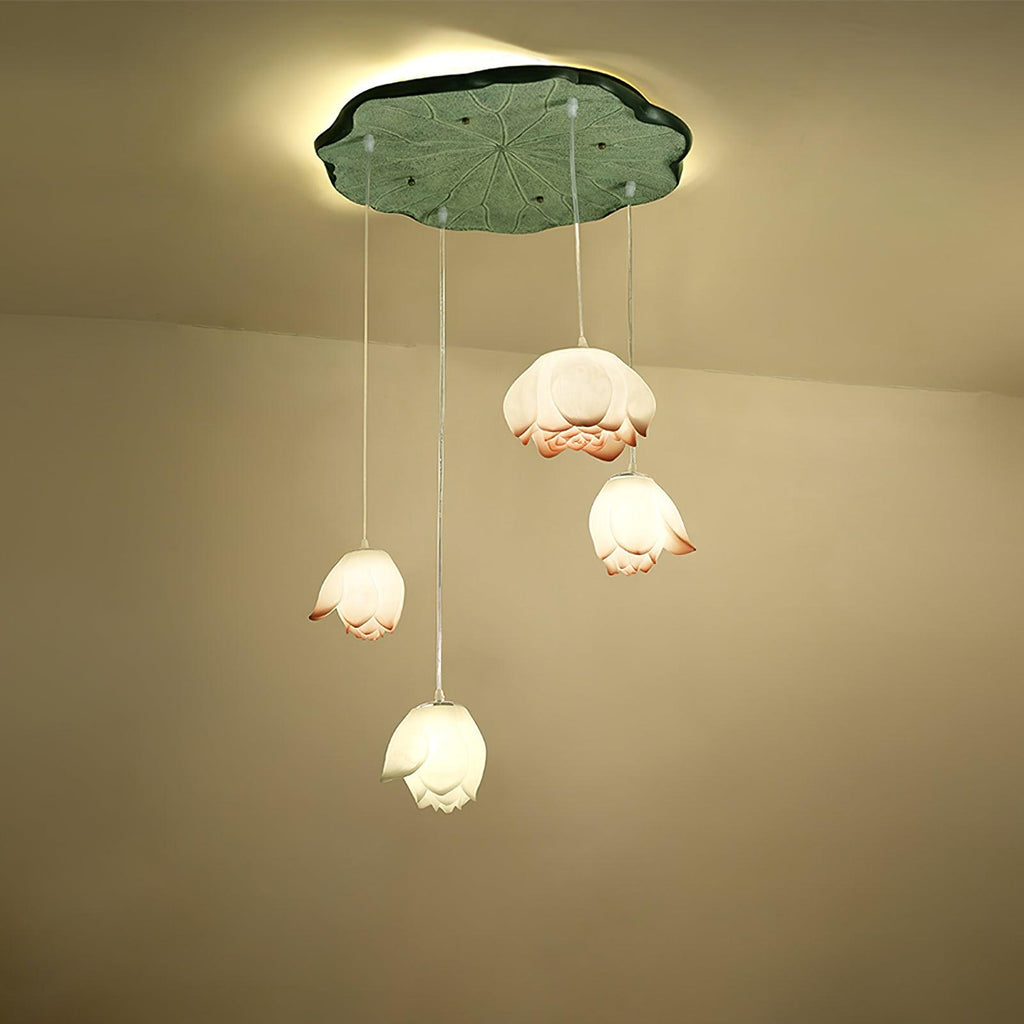 Four Clérachic water-lily pendants hang at different heights from a green lily-pad canopy, with white and coral-tipped buds glowing warm.