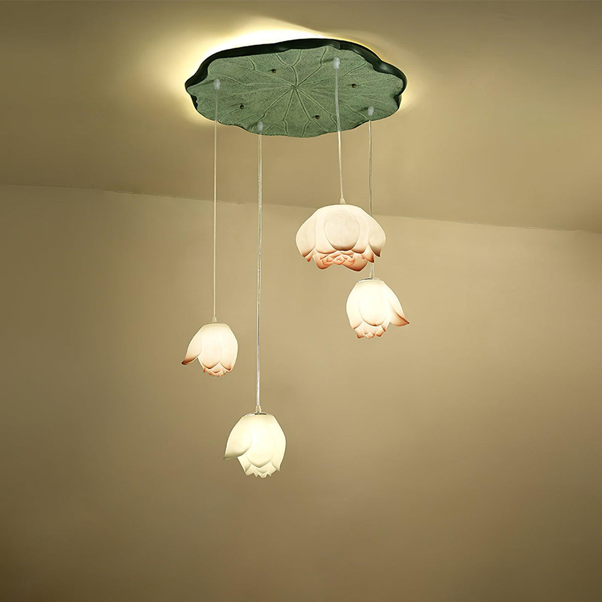 Four Clérachic water-lily pendants hang at different heights from a green lily-pad canopy, with white and coral-tipped buds glowing warm.