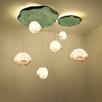 Six Clérachic water-lily pendants arranged beneath two green lily-pad canopies, with white and coral-tipped buds at different heights.