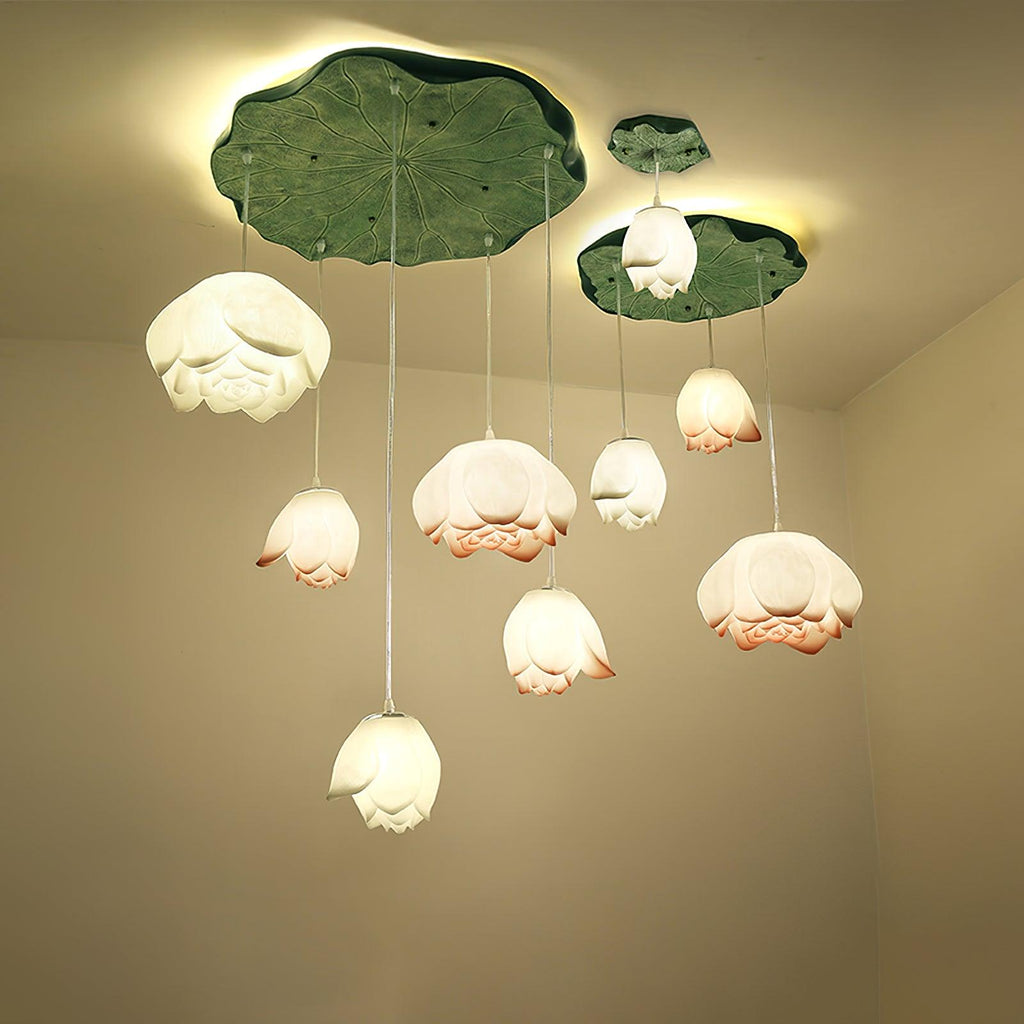 Looking up at a full Clérachic water-lily pendant cluster, the white and coral-tipped buds glow beneath lily-pad canopies against a cream wall.