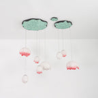 The Clérachic water-lily pendants hang on a white ceiling, with pink-tipped buds on long cords under two lily-pad canopies.