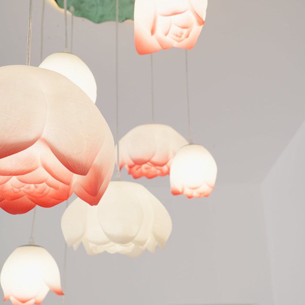 Close view of overlapping pink-tipped water-lily shades on this Clérachic chandelier, with pale blossoms hanging around them, lit from inside.