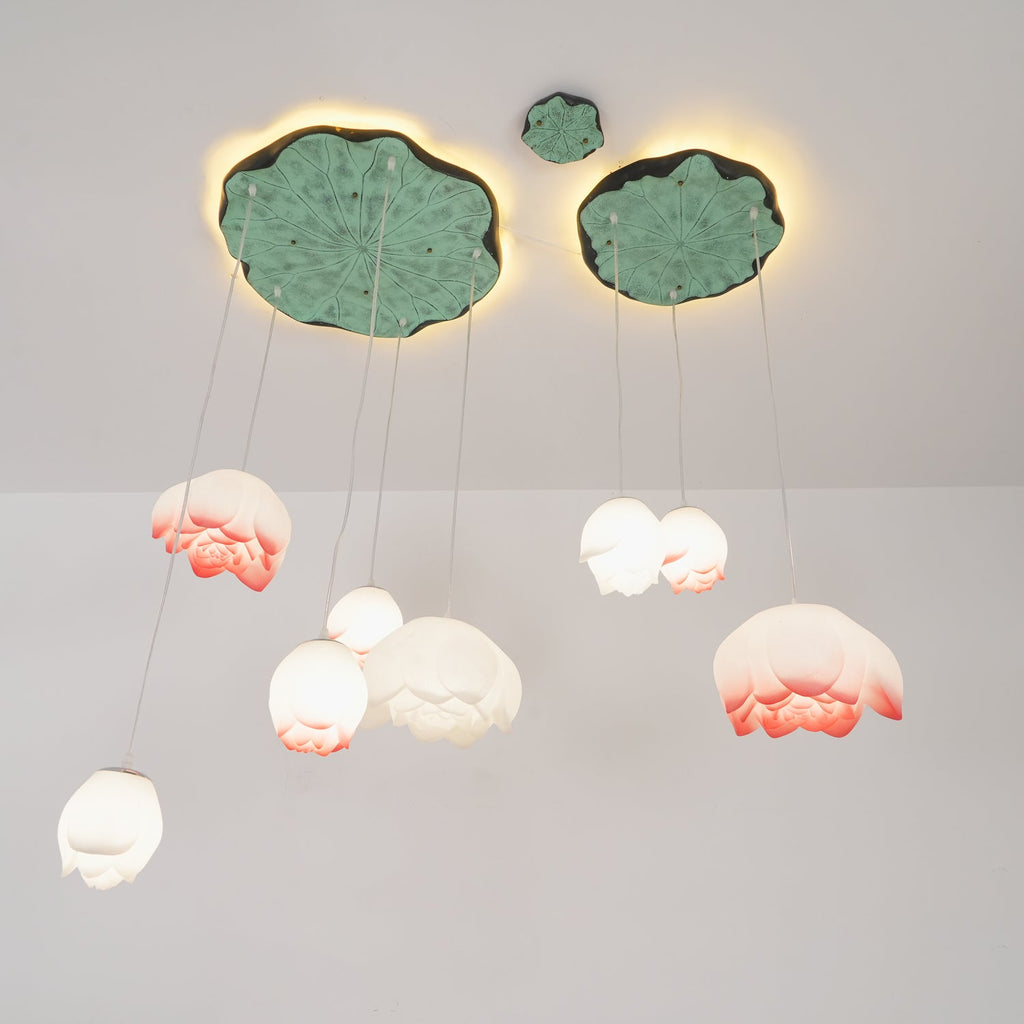 The Clérachic water-lily pendants seen from below, with pale buds hanging beneath two lily-pad canopies lit from behind.
