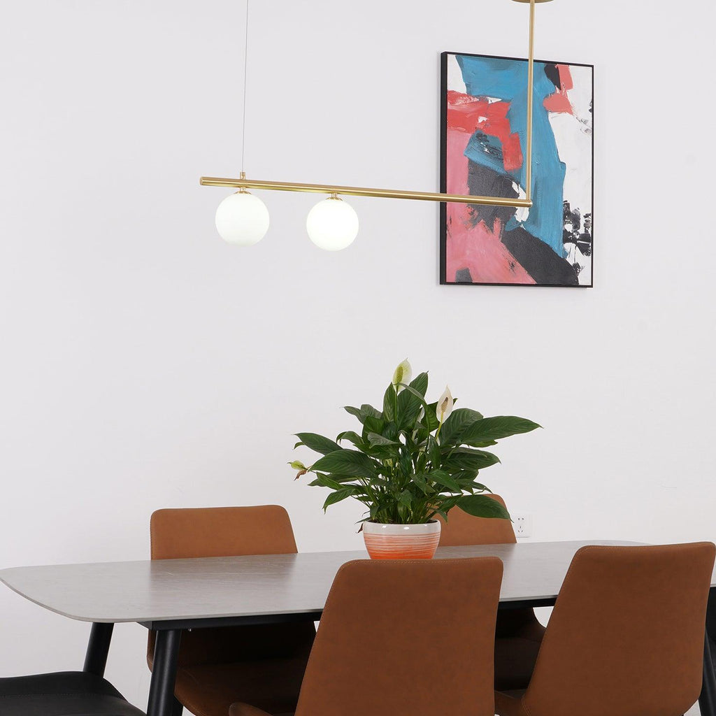 Clérachic gold pendant bar with two opal globes hanging in front of a bright abstract print, above a table with a plant.