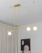Clérachic gold pendant with three globes hung beside a cream curtain, with a framed arch print on the wall below.