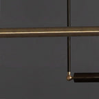 Close view of the darker brass bar and the black rod and swivel joint of this Clérachic pendant, on a charcoal background.