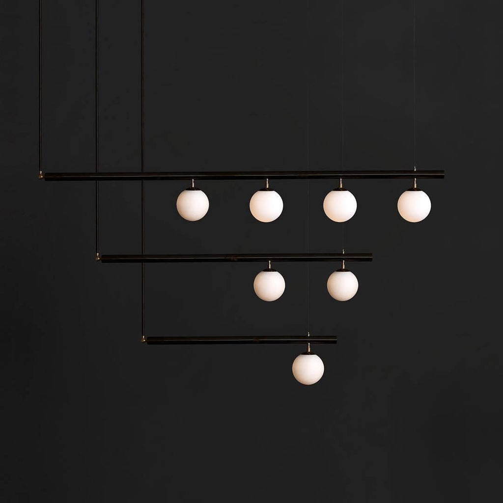 Black Clérachic pendant with three stepped bars and seven lit globes, hanging against a charcoal background.