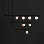 Black Clérachic pendant with three stepped bars and seven lit globes, hanging against a charcoal background.