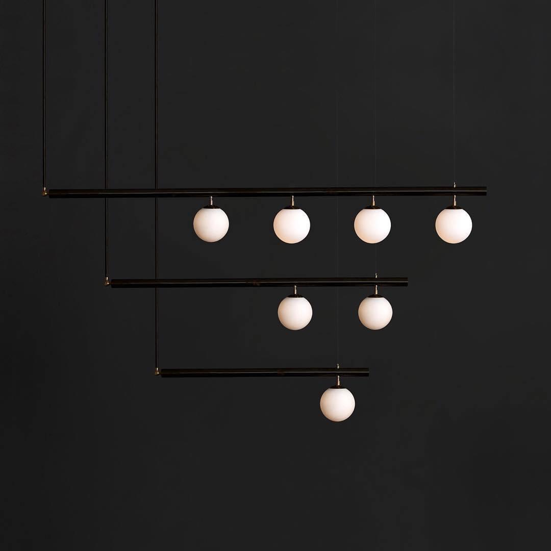 Black Clérachic pendant with three stepped bars and seven lit globes, hanging against a charcoal background.