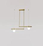 Three-globe Clérachic gold pendant with its ceiling plate, a bar of two and a bar of one, on a pale grey wall.