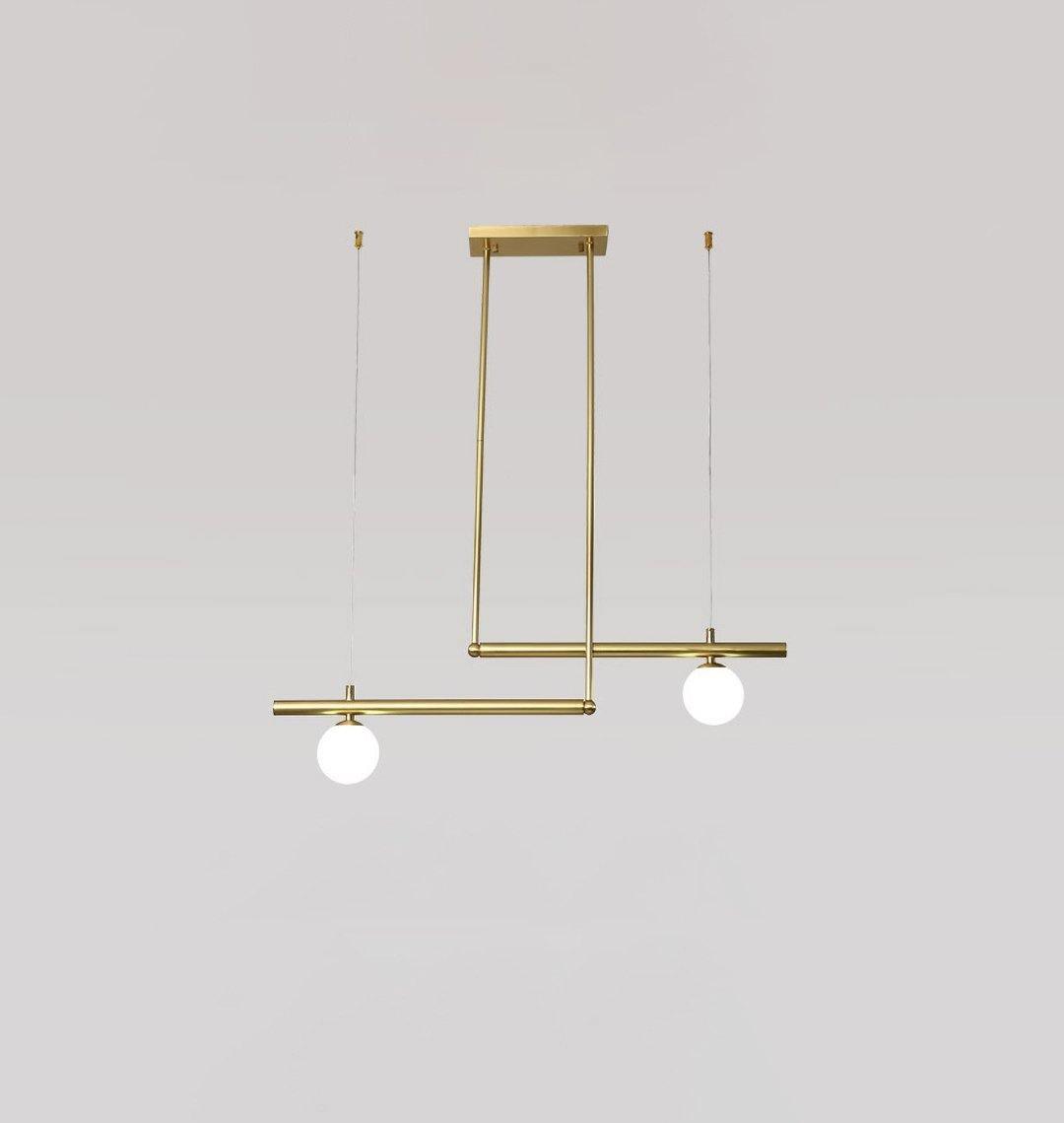Three-globe Clérachic gold pendant with its ceiling plate, a bar of two and a bar of one, on a pale grey wall.