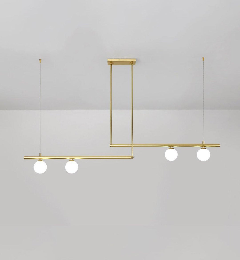 Clérachic gold pendant with four opal globes on two offset bars, hung from a rectangular plate on a pale grey wall.