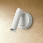 Clérachic matte white wall reading light with a pivoting cylinder head and a small slide switch, shown unlit on a plaster wall.