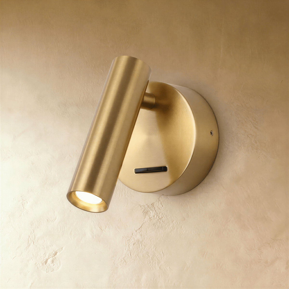 Clérachic brushed brass wall reading light, a slim cylinder head tilted down over a round backplate and slide switch.