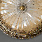 Close view from below of the pleated glass and the small brass centre boss on this Clérachic ceiling light.