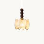 A Clérachic pendant with a gathered cream fabric shade printed with fine botanical sketches, hung beneath three walnut-toned wooden beads, on white.