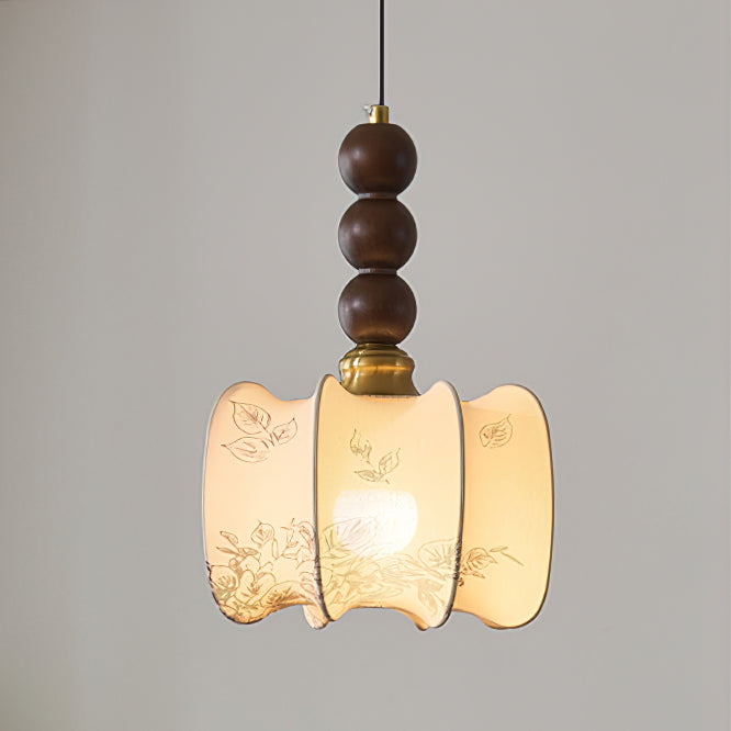 Close view of the gathered, scalloped shade of this Clérachic pendant, printed with botanical sketches, under a brass cap and walnut beads.