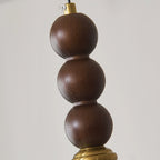 Close view of the three stacked walnut-toned beads and the brass collar at the top of this Clérachic pendant.