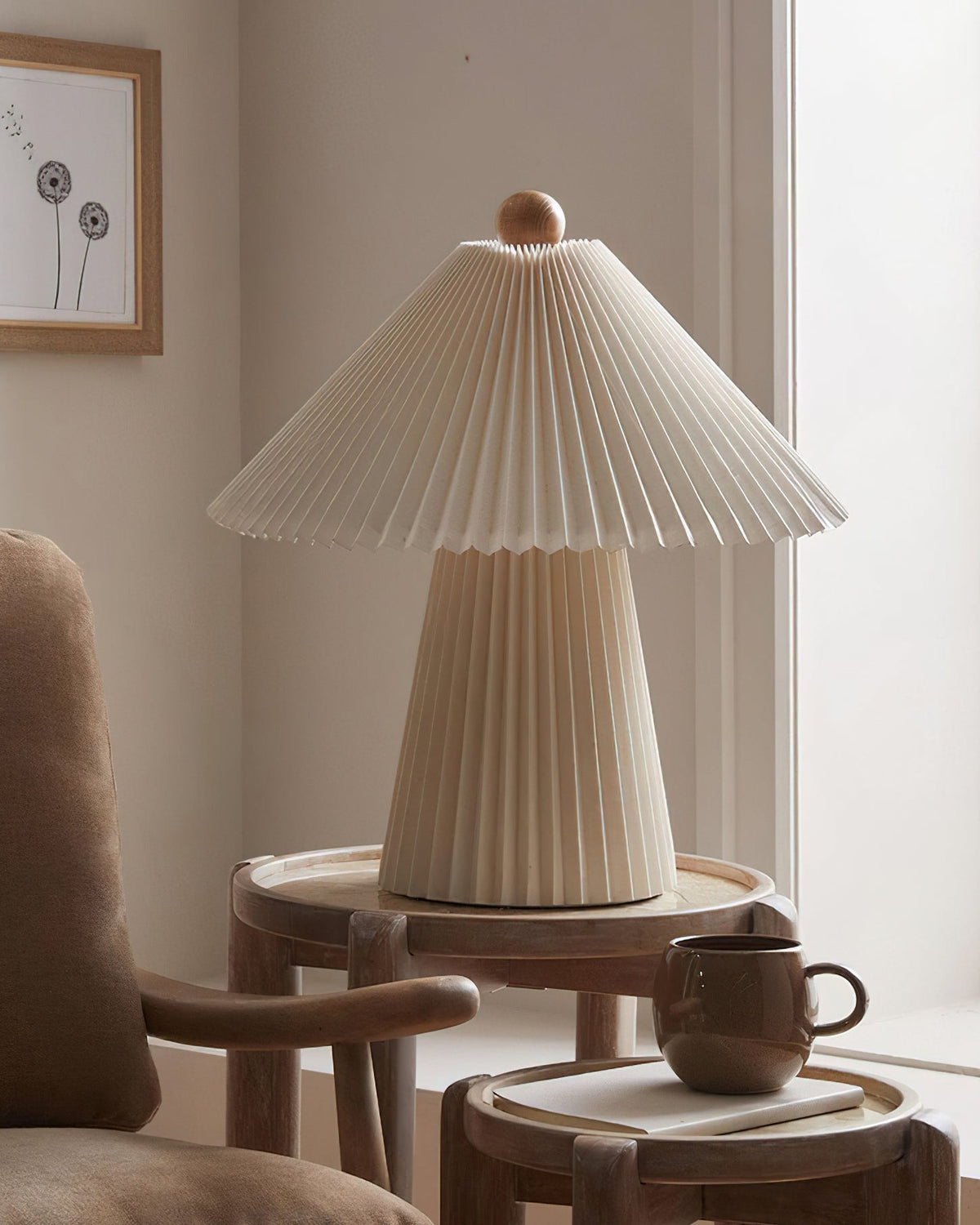 A cooler, grey-toned version of this Clérachic table lamp, unlit, on a round wooden side table beside a brown mug.