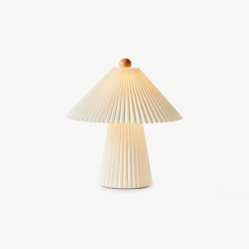 Smaller Clérachic table lamp with a pleated beige shade, wooden finial and a tapered pleated base, on a plain light backdrop.
