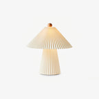 Smaller Clérachic table lamp with a pleated beige shade, wooden finial and a tapered pleated base, on a plain light backdrop.