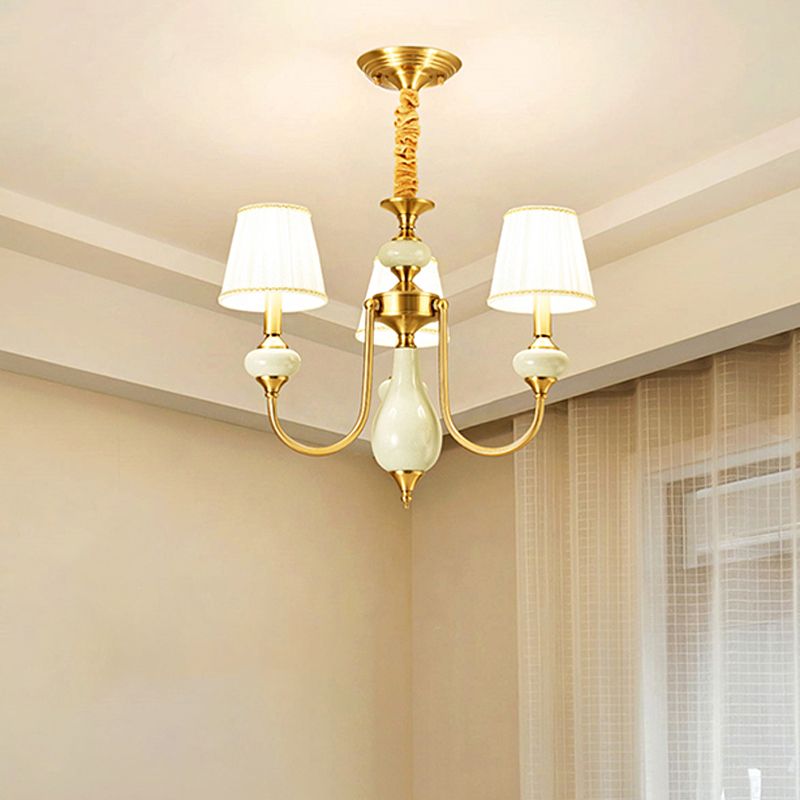 The Clérachic Pleated Blue Fabric Chandelier's 3-light version mounted in a bedroom corner, its pleated shades glowing beside a sheer curtain.