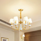 The Clérachic Pleated Blue Fabric Chandelier's 6-light version lit above an open living space, with a matching wall sconce glowing nearby.