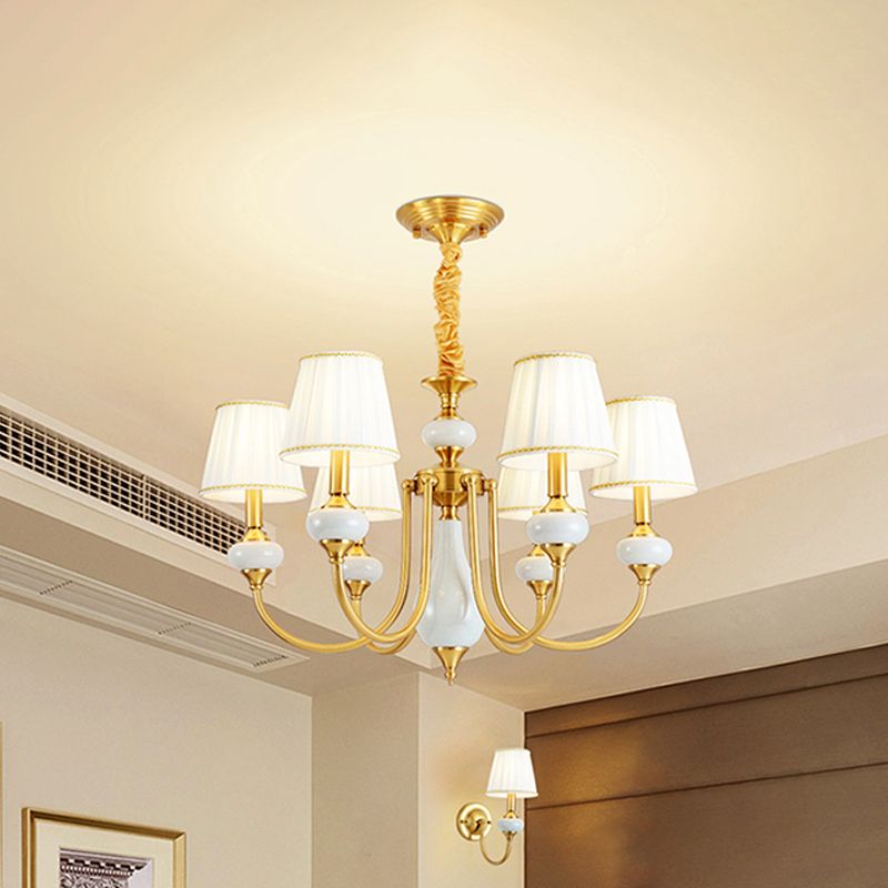 The Clérachic Pleated Blue Fabric Chandelier's 6-light version lit above an open living space, with a matching wall sconce glowing nearby.